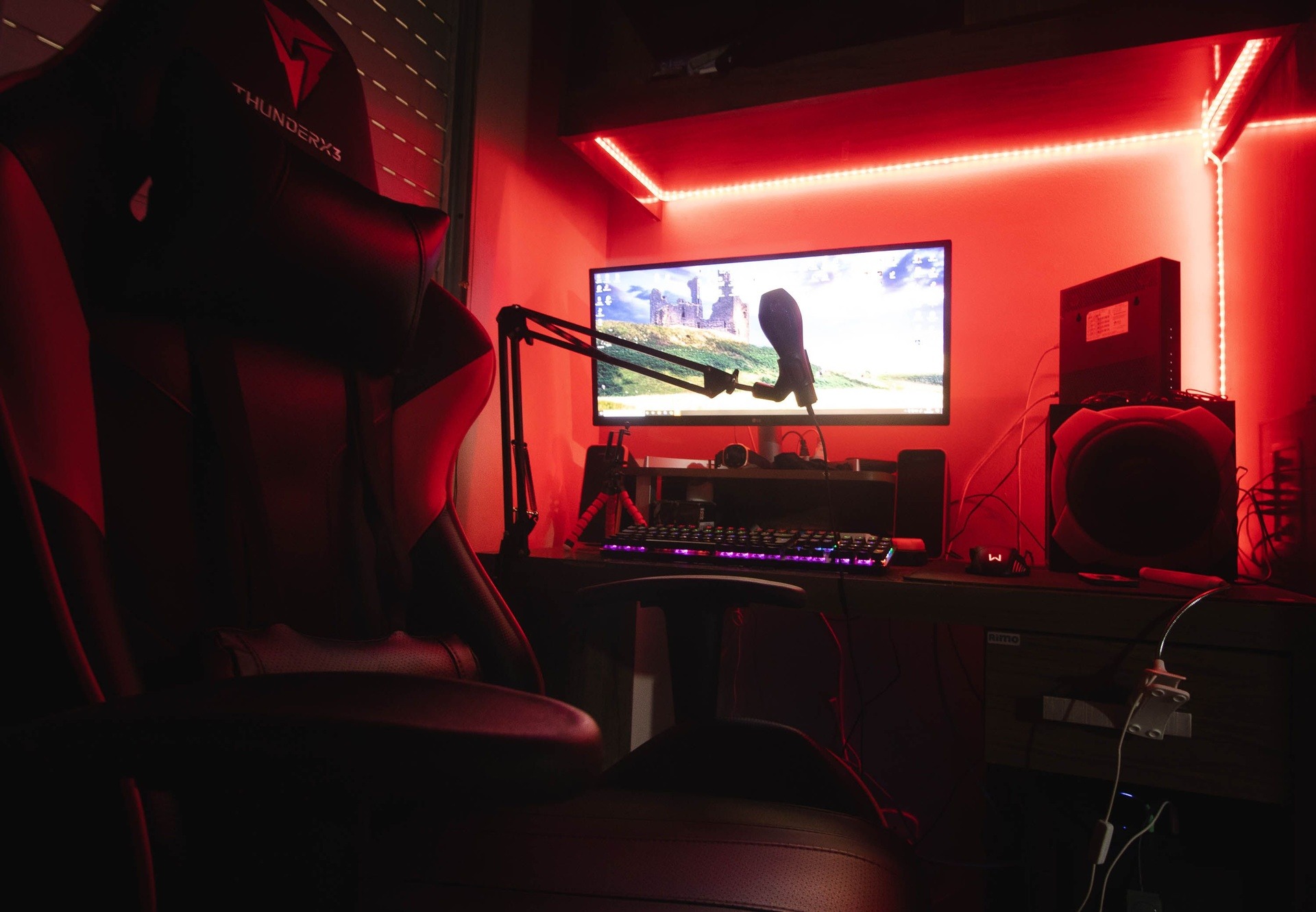 Streamer într-o cameră neon cu microfon și două monitoare